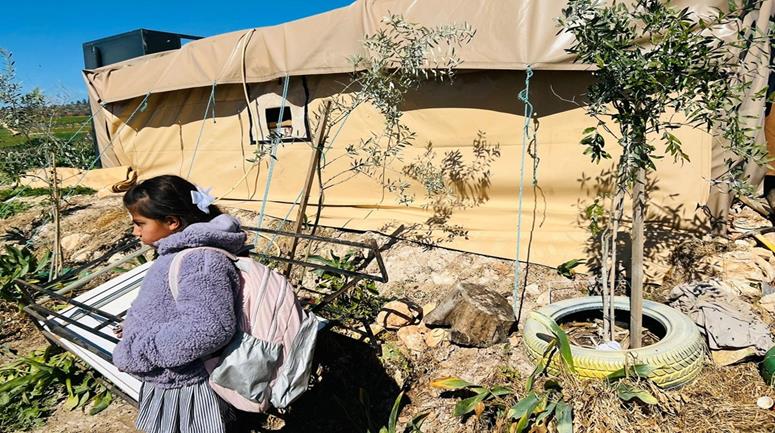 طالبة تقف أمام الخيمة المتواضعة التي يتلقى فيها طلبة خربة ابزيق تعليمهم بعد تخريب المستعمرين لمحتويات مدرستهم وتدمير الطريق الواصل إليها (تصوير: إسراء غوراني/وفا)